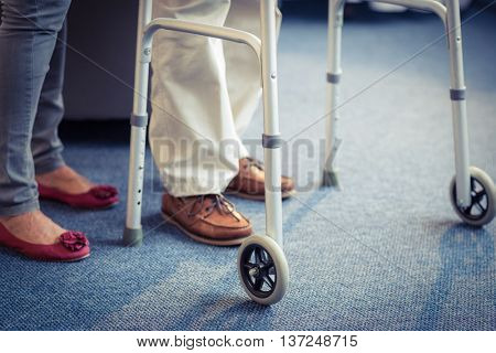 Senior woman helping senior man to walk with walker