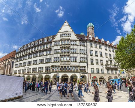 MUNICH GERMANY - MAY 27 2016: people in the pedestrian zone with view of Hirmer the largest men's fashion house in the world with decoration in Munich Germany