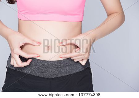 woman pinch stomach with isoltaed with gray backgroundasian