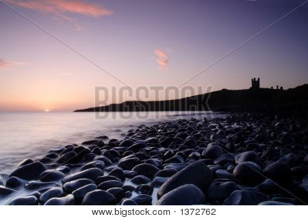 Východ slunce nad skály v Dunstanburgh Castle
