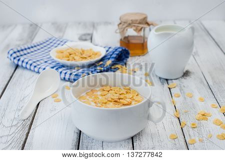 Cornflakes and milk on white wooden background. Morning breakfast. Rustic style.