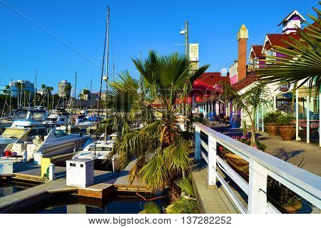 June 29, 2016 in Long Beach, CA:  Yachts and sail boats docked at the Long Beach Harbor taken at Shoreline Village where people can shop and dine at the colorful buildings overlooking the marina