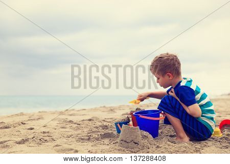 little boy play with sand on tropical beach