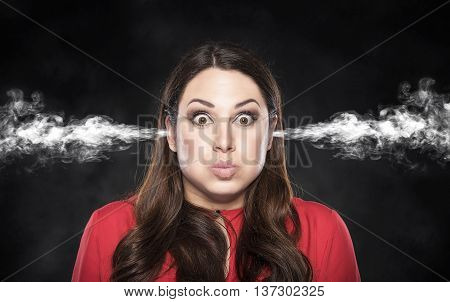 Smoke from the ears of a woman on a dark background. Overvoltage - concept.