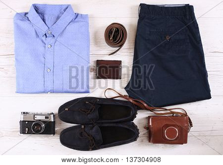Set of male casual clothing and retro photocamera on wooden background