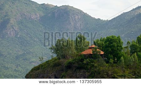 The house stands on a hill amidst the jungle and mountains in the background