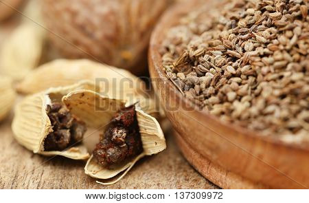 Cardamom seeds with other spices on wooden surface