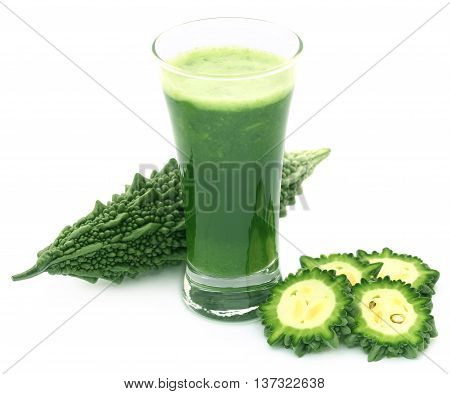 Herbal juice of green momodica in a glass with sliced vegetables
