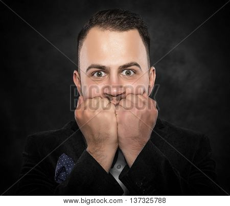 Excited or scared young man on a dark background.