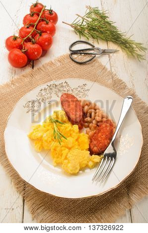 spanish breakfast with scrambled eggs on a plate chorizo baked beans fresh tomatoes rosemary and herbal scissor