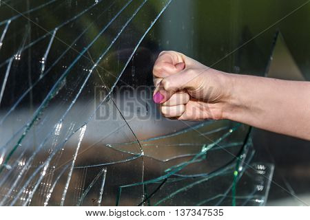 Female fist braking the glass window outdoors