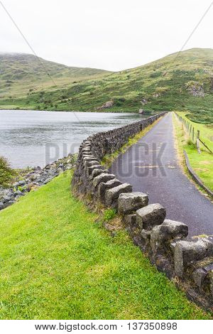 Dull day dam of Llyn Cwmystradllyn reservoir near Portmadog Gwynedd Wales UK.