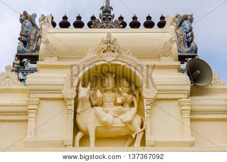 Tamil Nadu India - October 18 2013: Cream-colored statue of Lord Shiva and Parvati on their bull at Pillayarpatti Karpaga Vinayagar temple entrance.