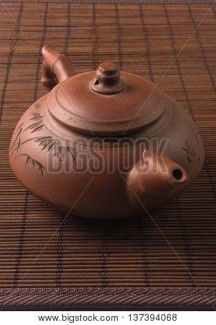 brown Chinese teapot of Yixing clay with traditional ornament on bamboo Mat