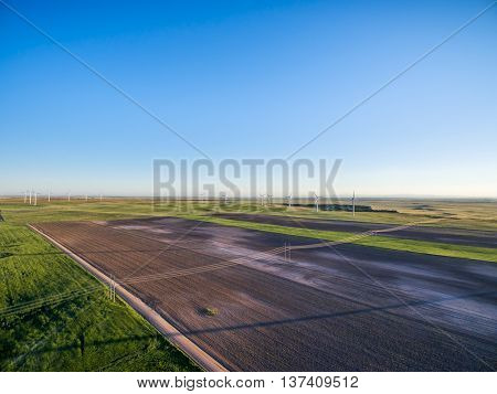 aerial view of farmland in eastern Colorado - plowed field, green meadows, dirt road and wind farm at Pawnee National Grassland near Grover