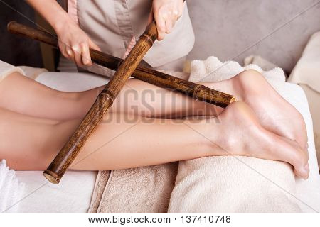 Woman having anti-stress massage with bamboo sticks. Spa Salon rejuvenating body massage