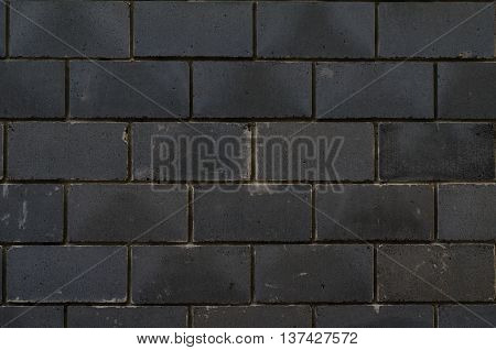 Background of black tiles on a house facade cladded in the pattern of bricks