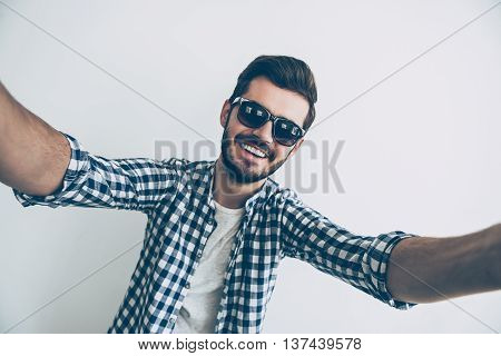 Selfie time! Studio shot of handsome young man making selfie and smiling