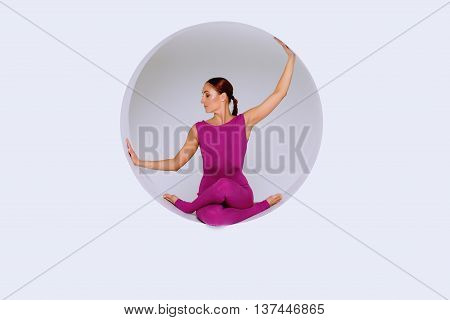 sporty woman in pink active wear practicing yoga exercises in geometric design of round shapesin sphere. Studio shot white background. Creative concept of sports.