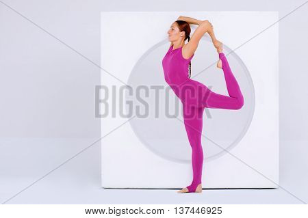 stylish and Attractive woman in active wear stretching legs in modern and white interior. background of geometric designs . Creative concept sports.