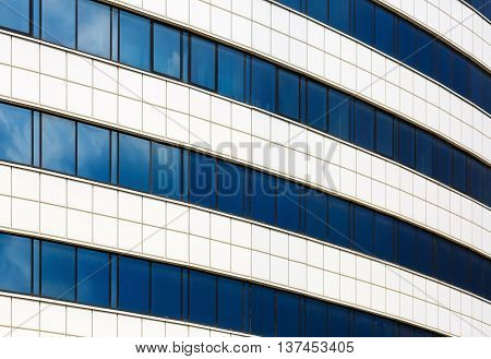 Facade of a modern building of steel and glass. Modern industrial architecture. Reflection of blue sky with clouds in the windows.