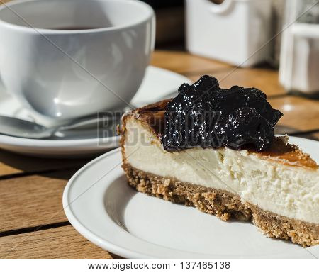 Slice of yummy blackcurrant cheesecake with tea