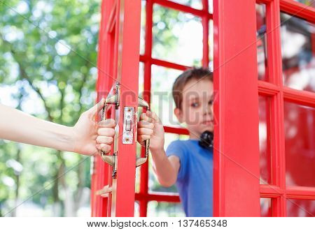 confidential phone conversation in a telephone box. Teenager talking on the phone, the adult tries to intervene. child protects the right to privacy from parents. concept of personal life, misunderstanding between children and parents.