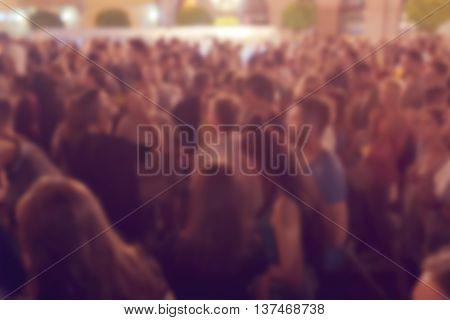 Unrecognizable crowd of young people at outdoor summer night party defocussed blur youth as background