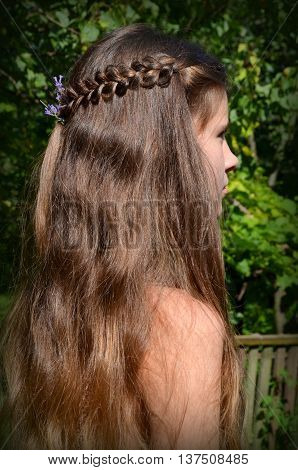 Young girl with long hair and the fine weave in the hair on the nature background
