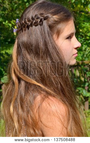 Young girl with long hair and the fine weave in the hair on the nature background