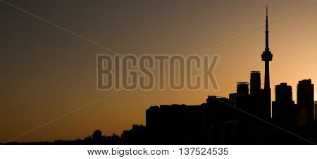 Silhouette of the Toronto skyline against an orange sky at sunset