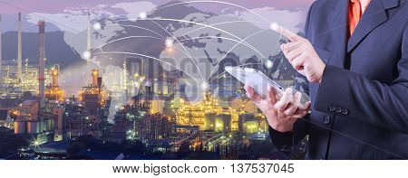 hand presses on world map with digital tabletIndustrial oil refinary background (Elements of this image furnished by NASA)
