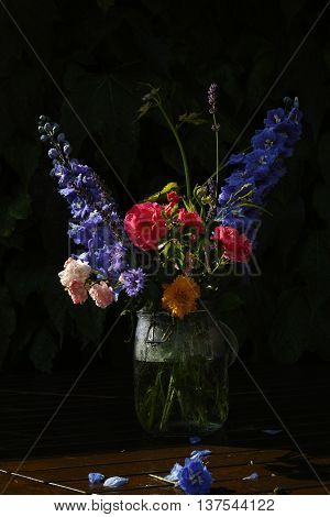 Sun after rain - colorful flowers bouquet in the garden with roses lavendel grape leaves and blue delfinium