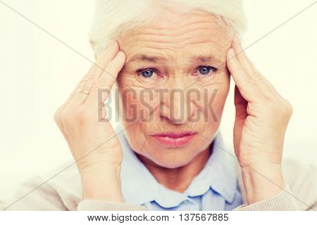 health care, pain, stress, age and people concept - face of senior woman suffering from headache