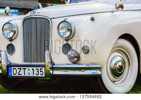 MINSK BELARUS - MAY 07 2016: Close-up of white Jaguar Mk VIII. This classic car was produced in the years 1956-1958. Front part of an vintage retro auto. Selective focus on the car's headlight.