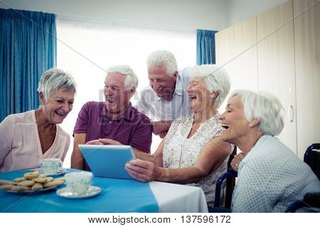 Group of seniors using a tablet computer in the retirement house