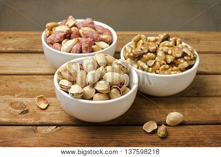 Assorted nuts in dishes on wooden table