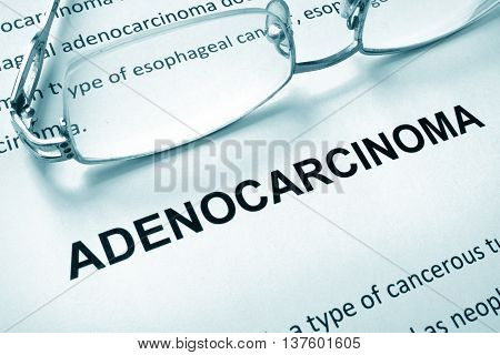 Paper with word adenocarcinoma and glasses. Medical concept.