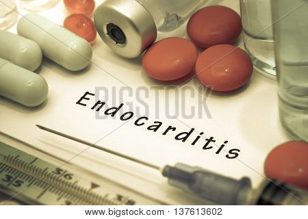 Endocarditis - diagnosis written on a white piece of paper. Syringe and vaccine with drugs.