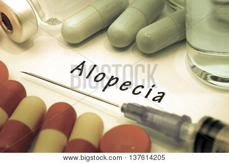 Alopecia - diagnosis written on a white piece of paper. Syringe and vaccine with drugs.