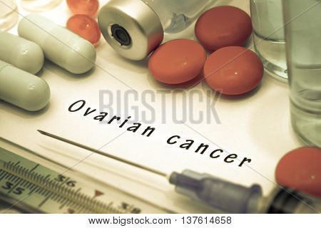Ovarian cancer - diagnosis written on a white piece of paper. Syringe and vaccine with drugs.