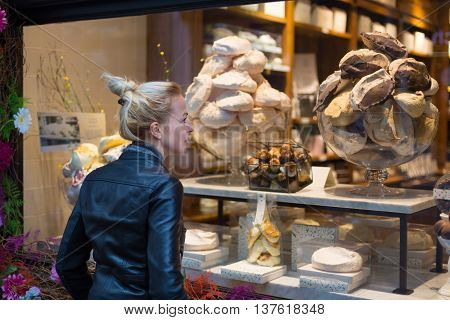 Lady window shopping in front of sinfully expensive chocolate boutique store display window. 