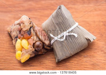 Two Zongzi or Asian Chinese sticky rice dumplings on wooden background. Zongzi is a traditional Chinese food eaten during the dragon boat festival.