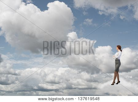 Smiling confident businesswoman in sky standing on cloud