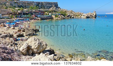 Paradise Bay, Malta - September 28, 2013. A popular swimming spot of Paradise Bay - a picturesque but narrow patch of sand backed by cliffs, with crystal clear water, with people and beach restaurants.