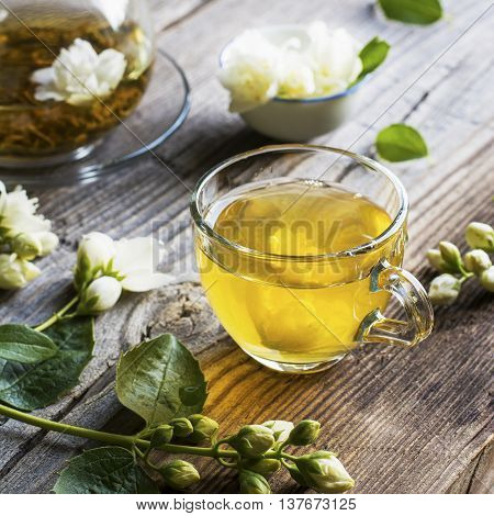 A cup of green tea infused with jasmine on a gray wooden background. selective focus