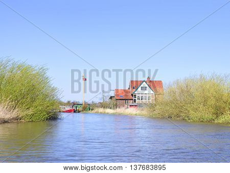 House at a riverside. Farm house in the sun. Sunny day at a river in North Germany.