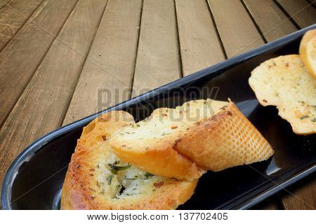 Close-up of a dish of garlic bread on wooden deck table