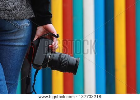 photographer holding camera close-up. Back view Selective focus. colored vertical stripes in the background.