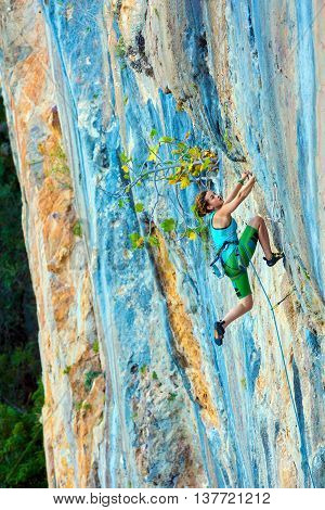 Female Climber Trying to keep Hold in last Effort to avoid deep fall down High rocky Wall in orange blue Colors Rope other Climbing Gear